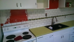 This shows the continuation of the subway tile as it goes behind the refrigerator.